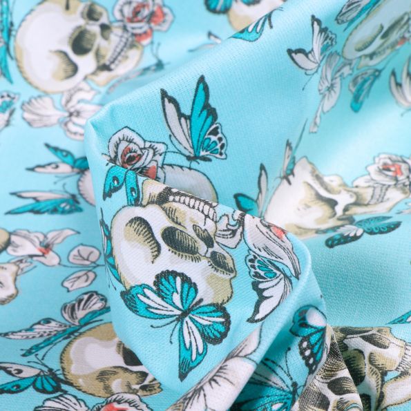 Tissu Coton enduit Têtes de mort et papillons sur fond Bleu turquoise - Par 10 cm