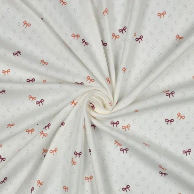 Tissu Jersey Coton ajouré Baby petits nœuds sur fond Blanc - Par 10 cm