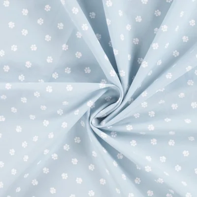 Tissu Popeline de Coton  patounes blanches Zumi sur fond Bleu ciel - Par 10 cm