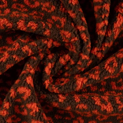Tissu Teddy Bouclettes motif léopard Orange sur fond Marron - Par 10 cm