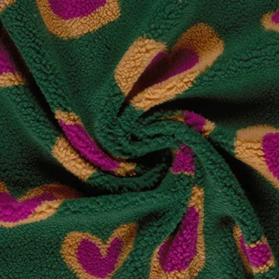 Tissu Bouclette Sherpa imprimé Coeurs Fuschia et Ocre sur fond Vert - Par 10 cm